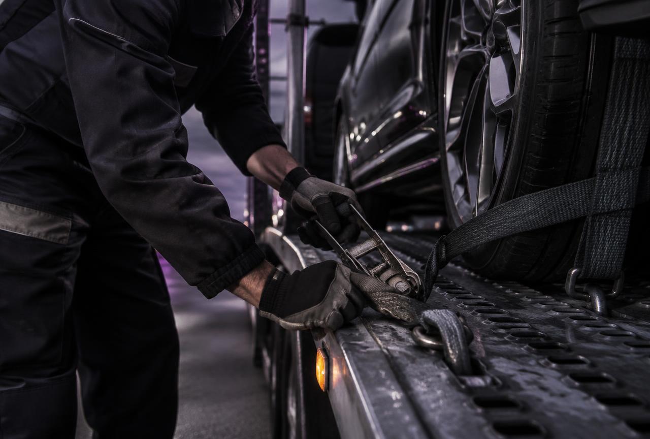Carrier driver ratcheting a wheel strap onto a loaded vehicle